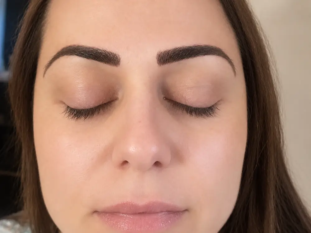 A client's face with the eyes closed, showing both brows after brow work.