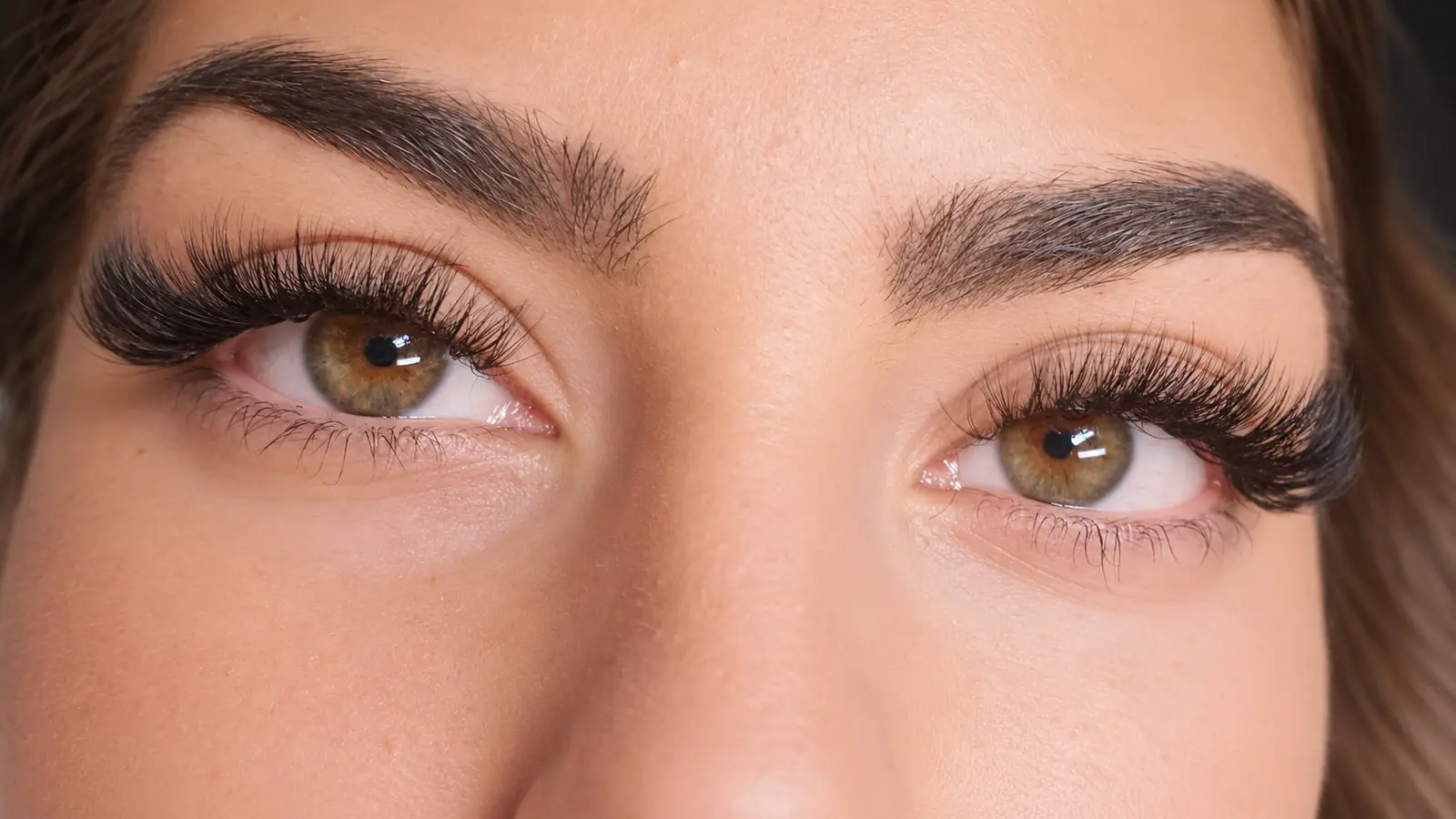 A client's eyes open, showing lash extensions on both eyes.